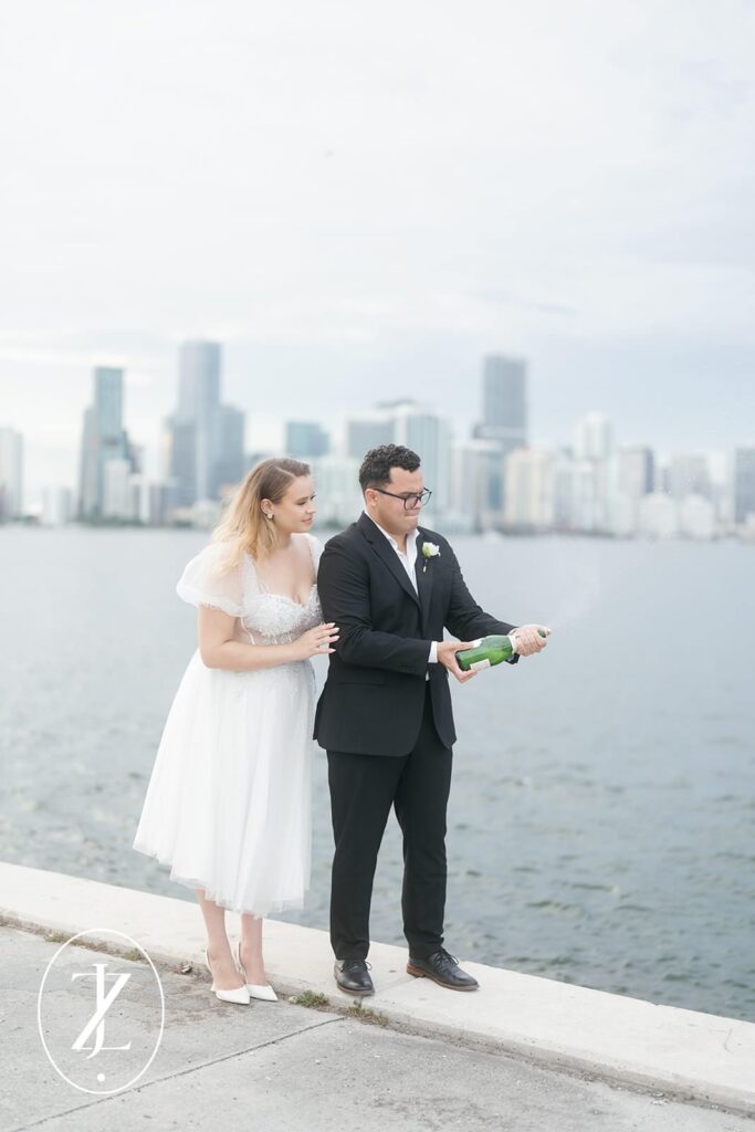 A couple opening a bottle of champagne celebrating their engagement